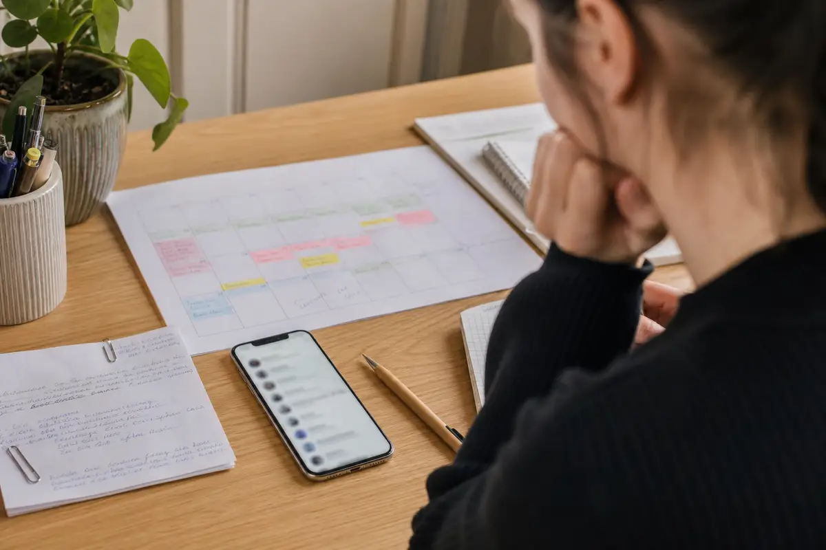 Smartphone anonyme, carnet et calendrier illustrant l’animation raisonnée d’un groupe de discussion privé