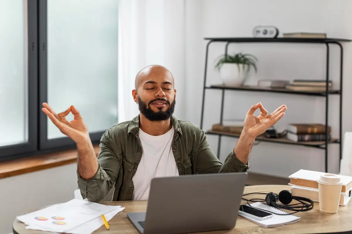 Bureau de travail rangé avec ordinateur sur support, clavier externe, bannette et câbles organisés près d’une fenêtre