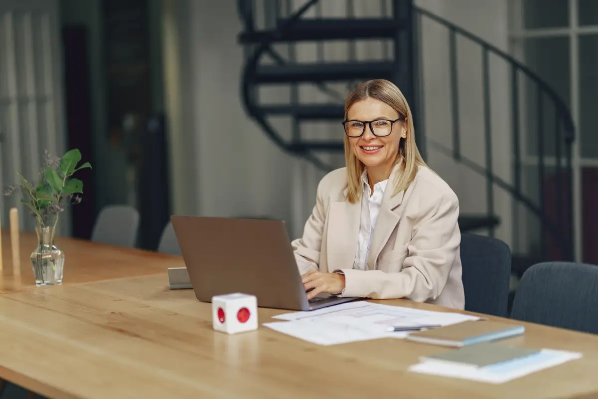 Professionnelle de dos préparant un projet de reconversion sur un bureau avec ordinateur, carnet et calendrier