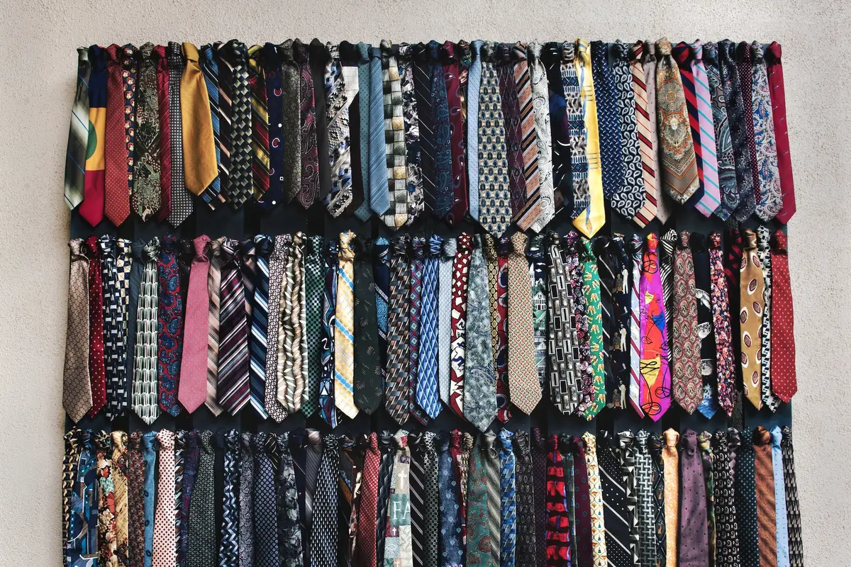 Cravates vintage décousues et transformées en bandeau, bracelet et nœud de barrette sur une table de couture
